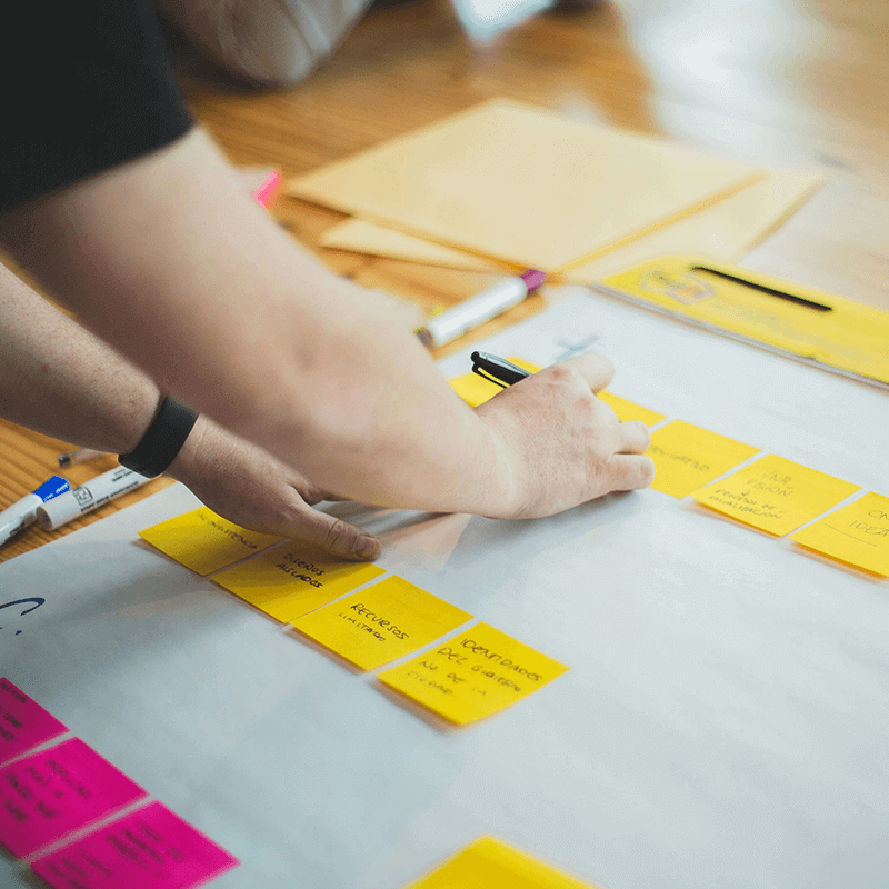 illustration-axe3-enseignement-mastere-specialise-eco-conseiller 2 bras d'un homme qui se penche sur un bureau plein de post-it et de dossiers