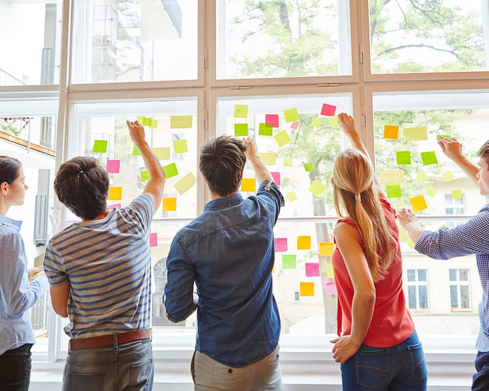 illustration-presentation-chantier Une équipe vue de dos écrivant sur une grande vitre