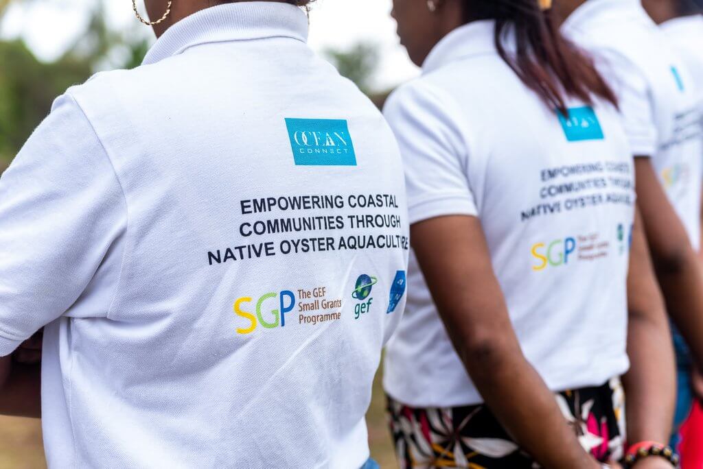 Femmes de dos avec un polo blanc. Texte sur le polo ainsi que le logo du small grants programme, GEF et des nations unis