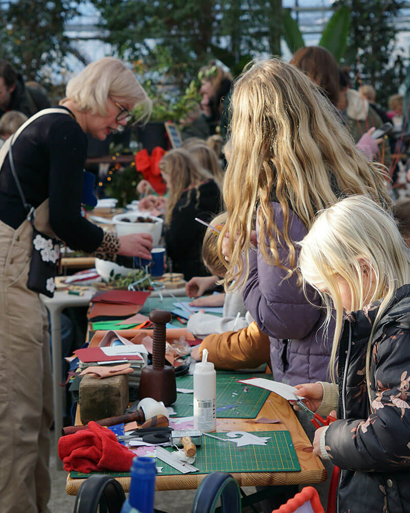 atelier-sensibilisation-mobilisation-ecologique-eco-conseil.svg stand de sensibilisation dehors tenue par une femme en salopette avec des enfants devant